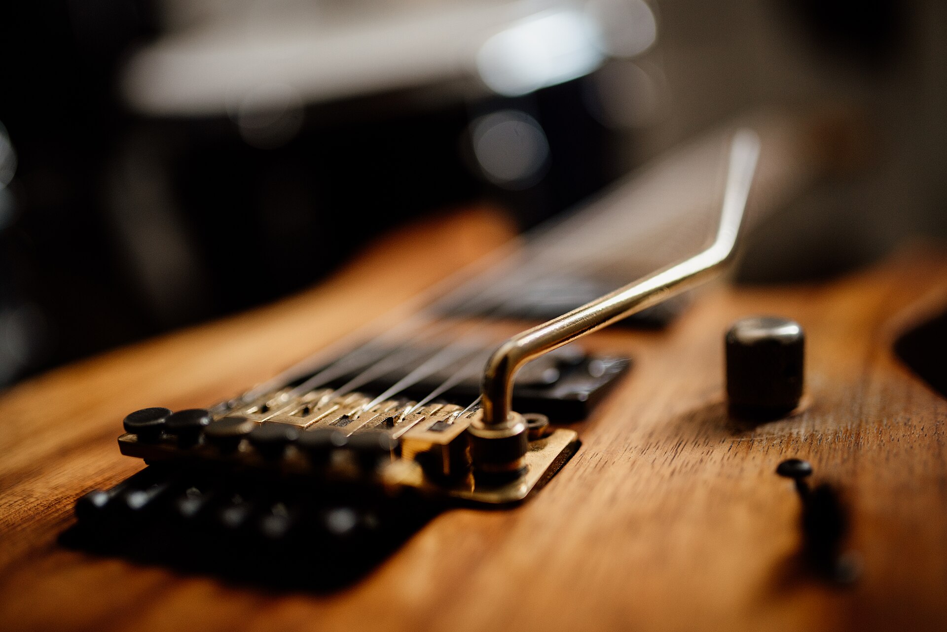 Close-up of a chrome Floyd Rose bridge and whammy bar on a natural wood guitar body