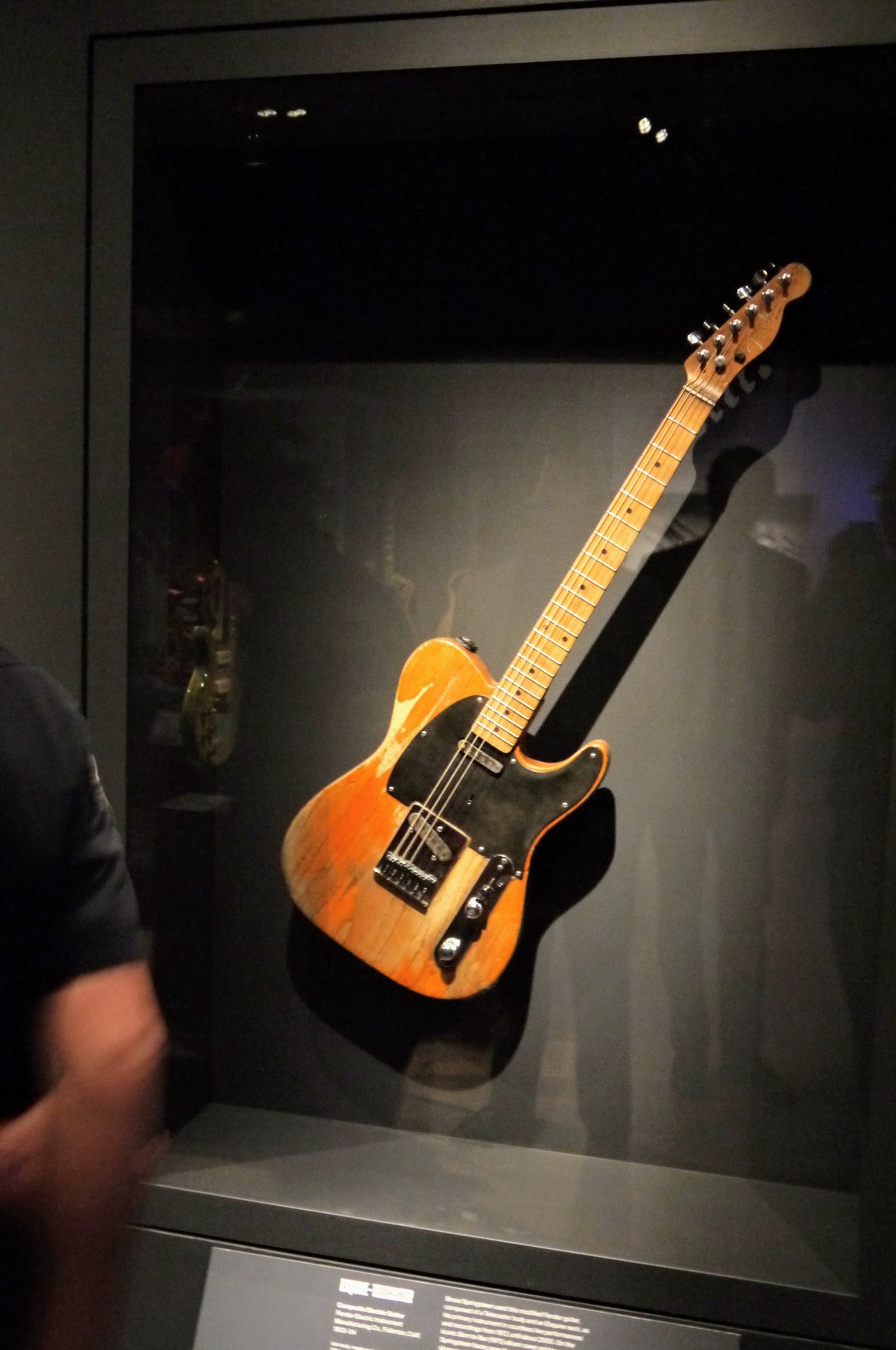 Bruce Springsteen's worn Esquire-Telecaster composite guitar displayed in a dark museum case