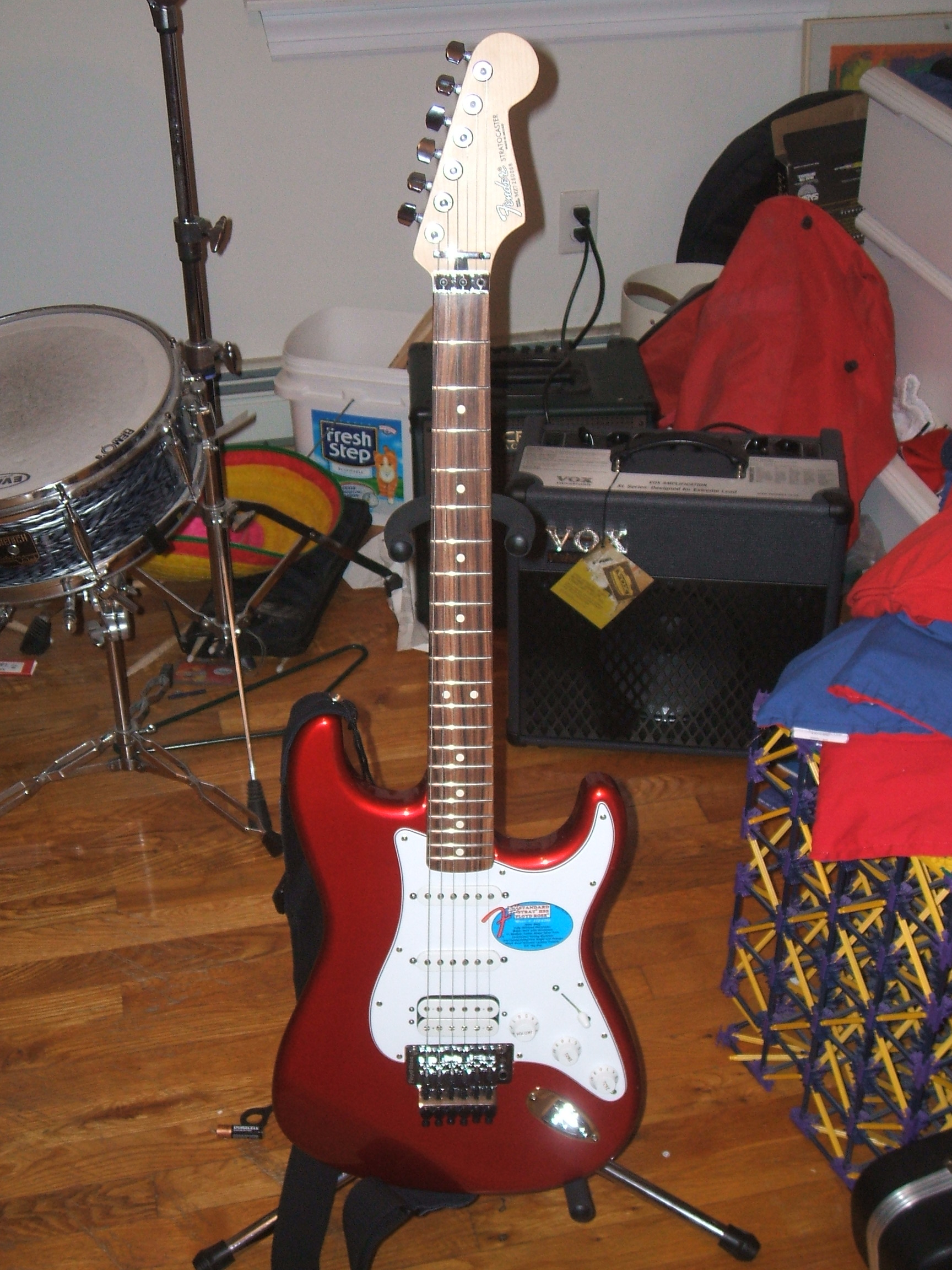 Red Stratocaster with a locking tremolo on a stand in a home studio
