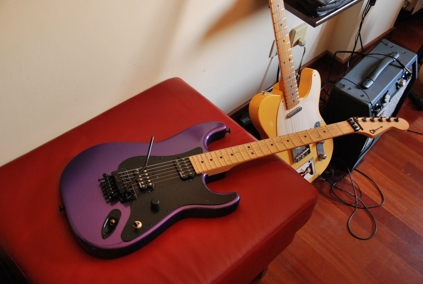 Purple Charvel Strat-style guitar with a maple neck lying on a red chair