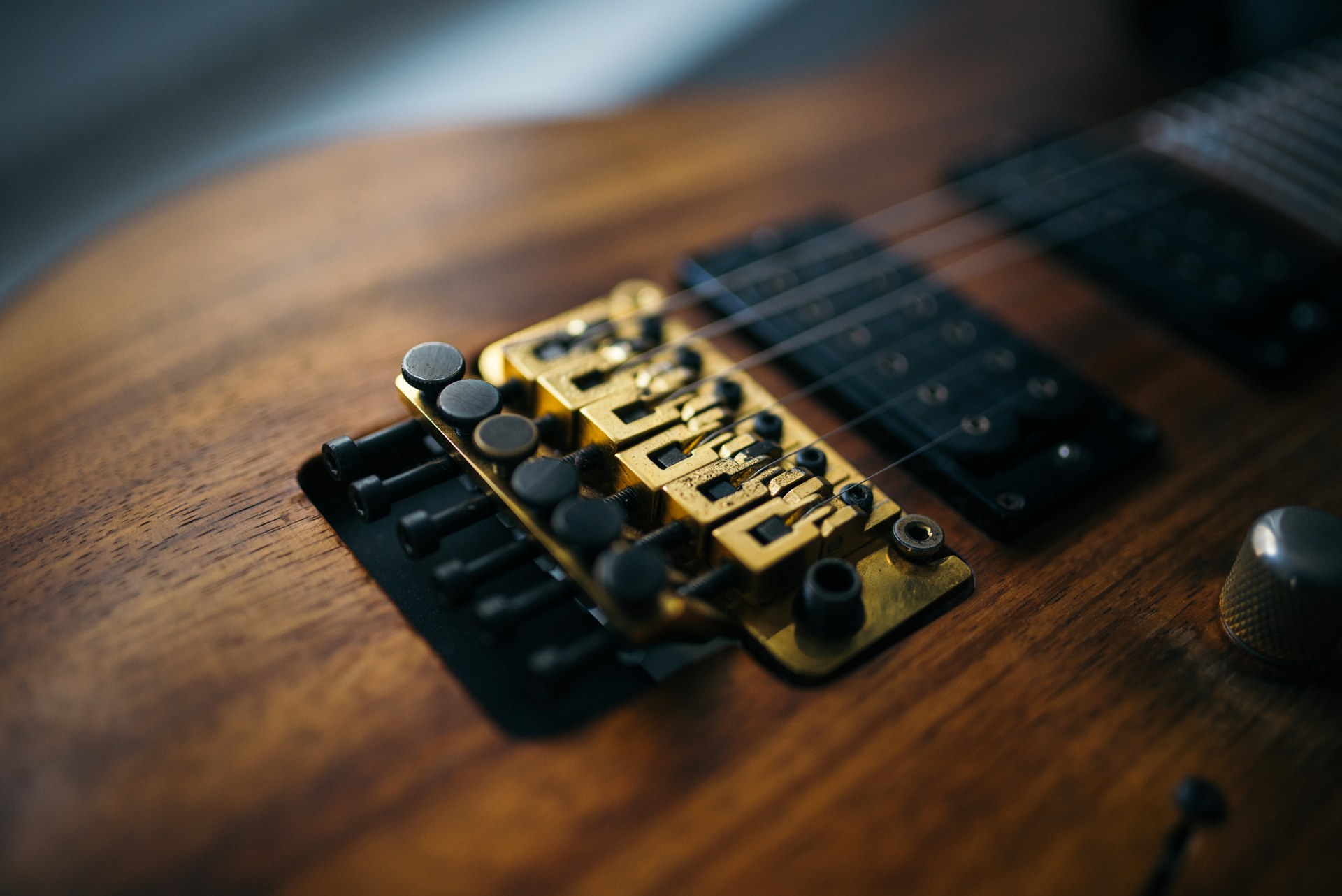 Gold locking tremolo bridge on a koa guitar body next to a humbucker