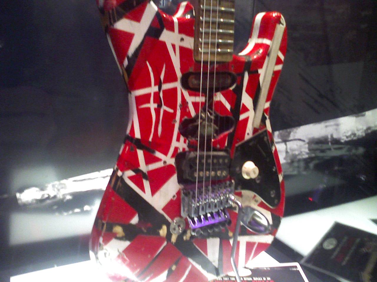 Red guitar with black and white stripes and a locking tremolo, close up under bright lights