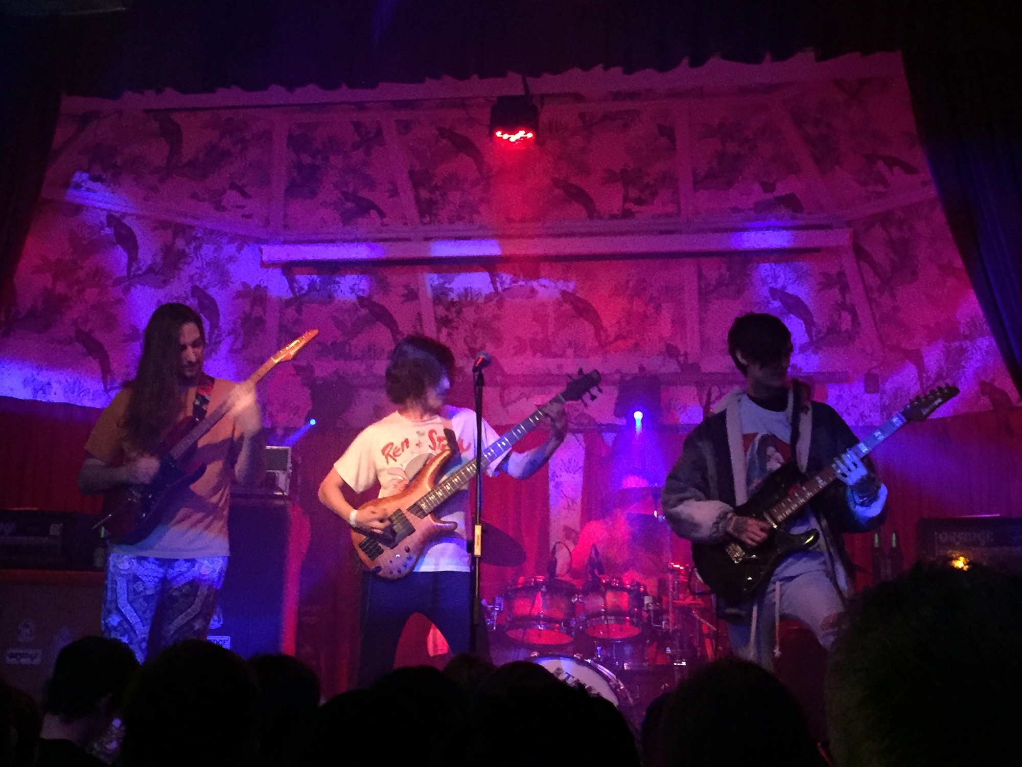 Polyphia performing under purple stage lights at a small venue in Manchester, UK