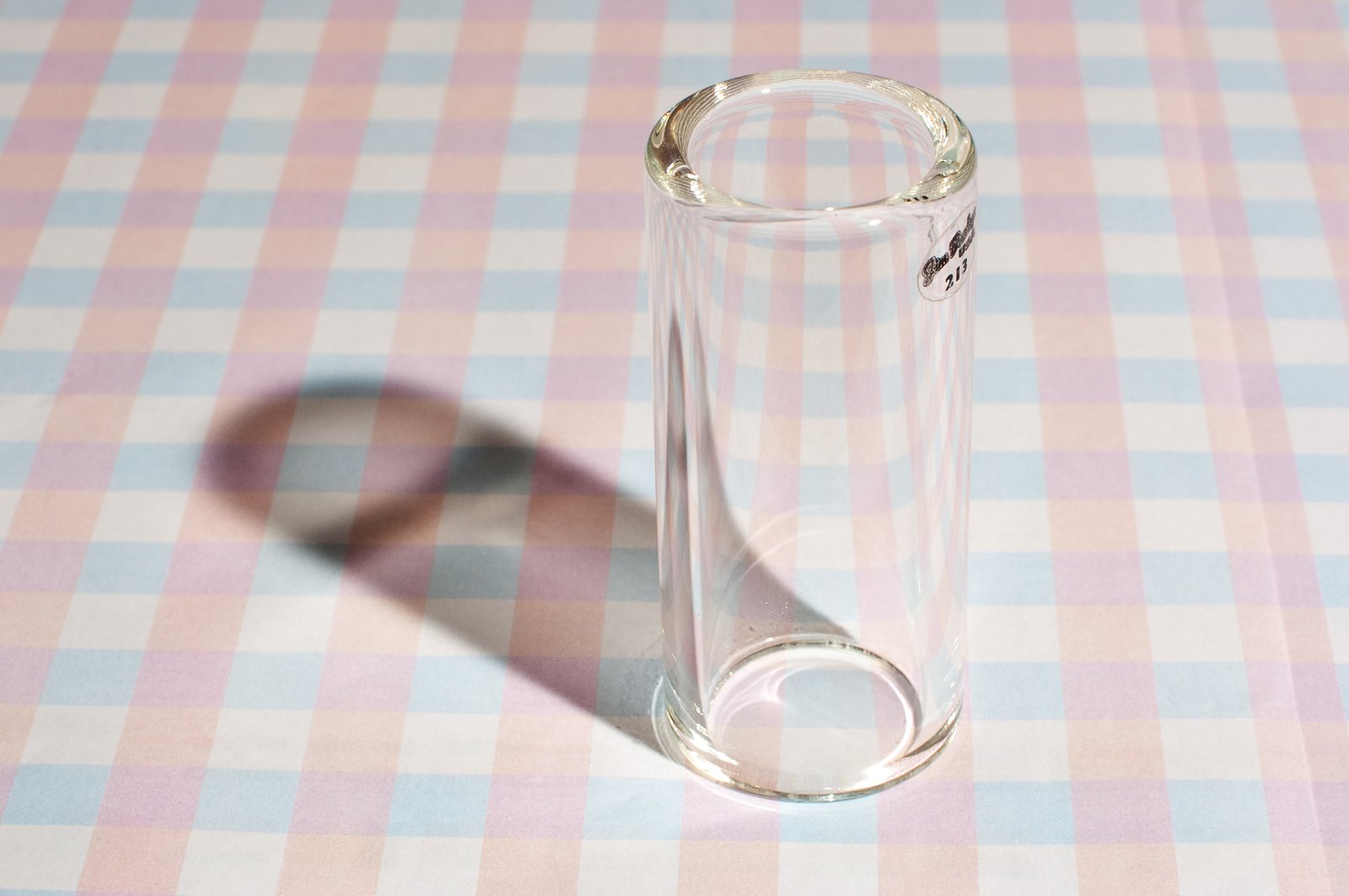 A clear borosilicate glass guitar slide on a grid background