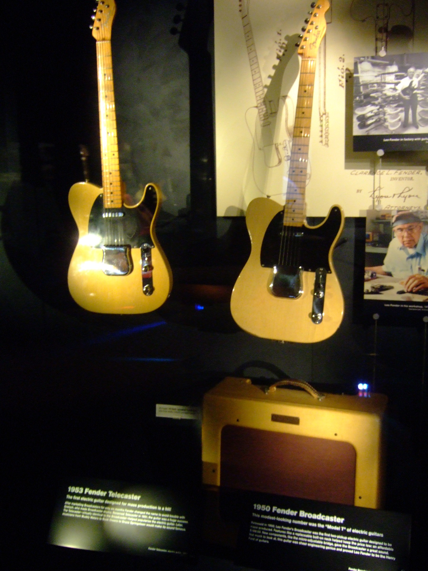 A 1950 Fender Broadcaster and a 1953 Fender Telecaster in a museum case, both with butterscotch finishes and black pickguards