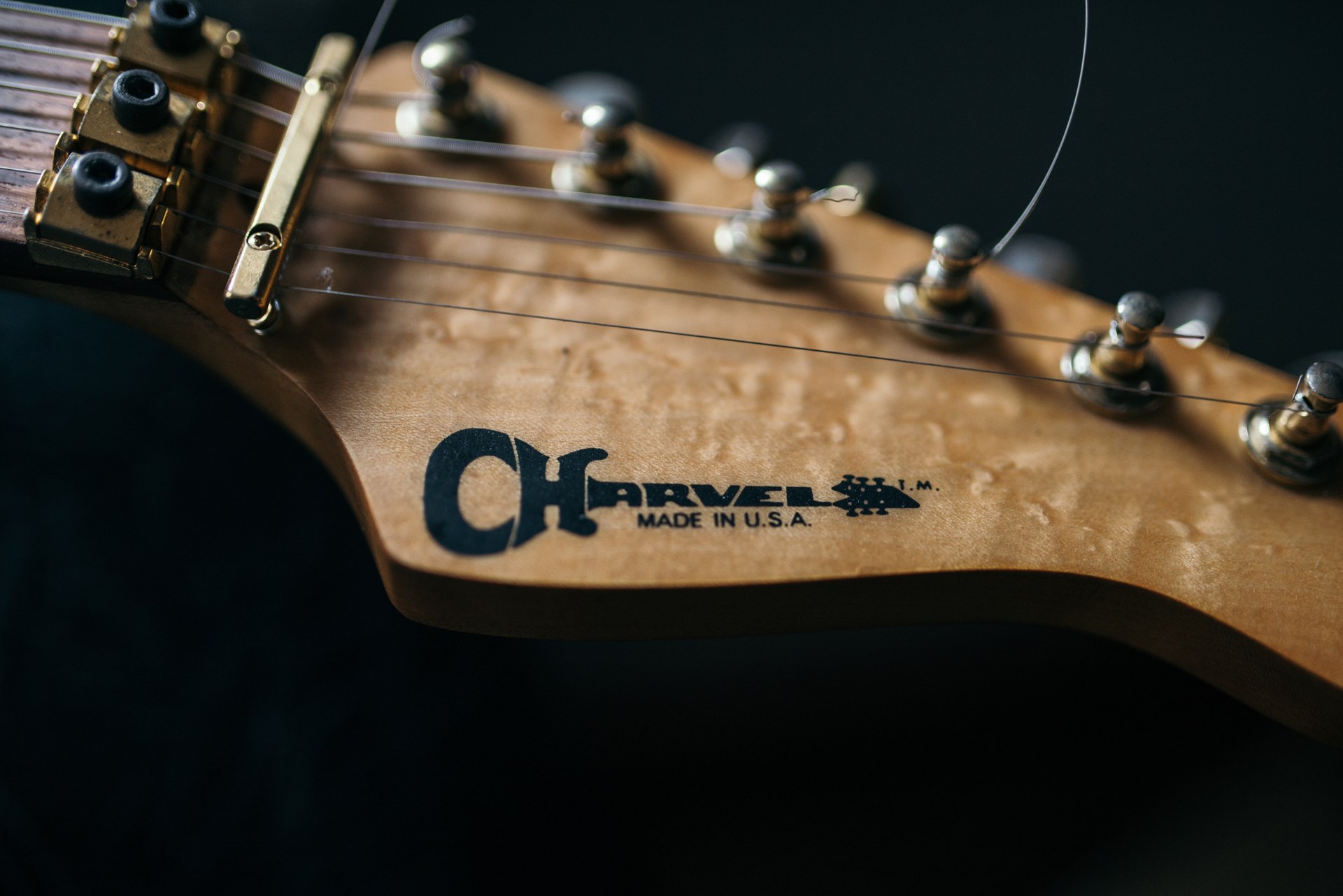 Close-up of a maple headstock with the Charvel logo and chrome tuners