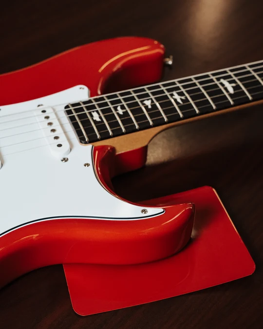 Close-up of a red PRS Silver Sky guitar with white pickguard and bird inlays
