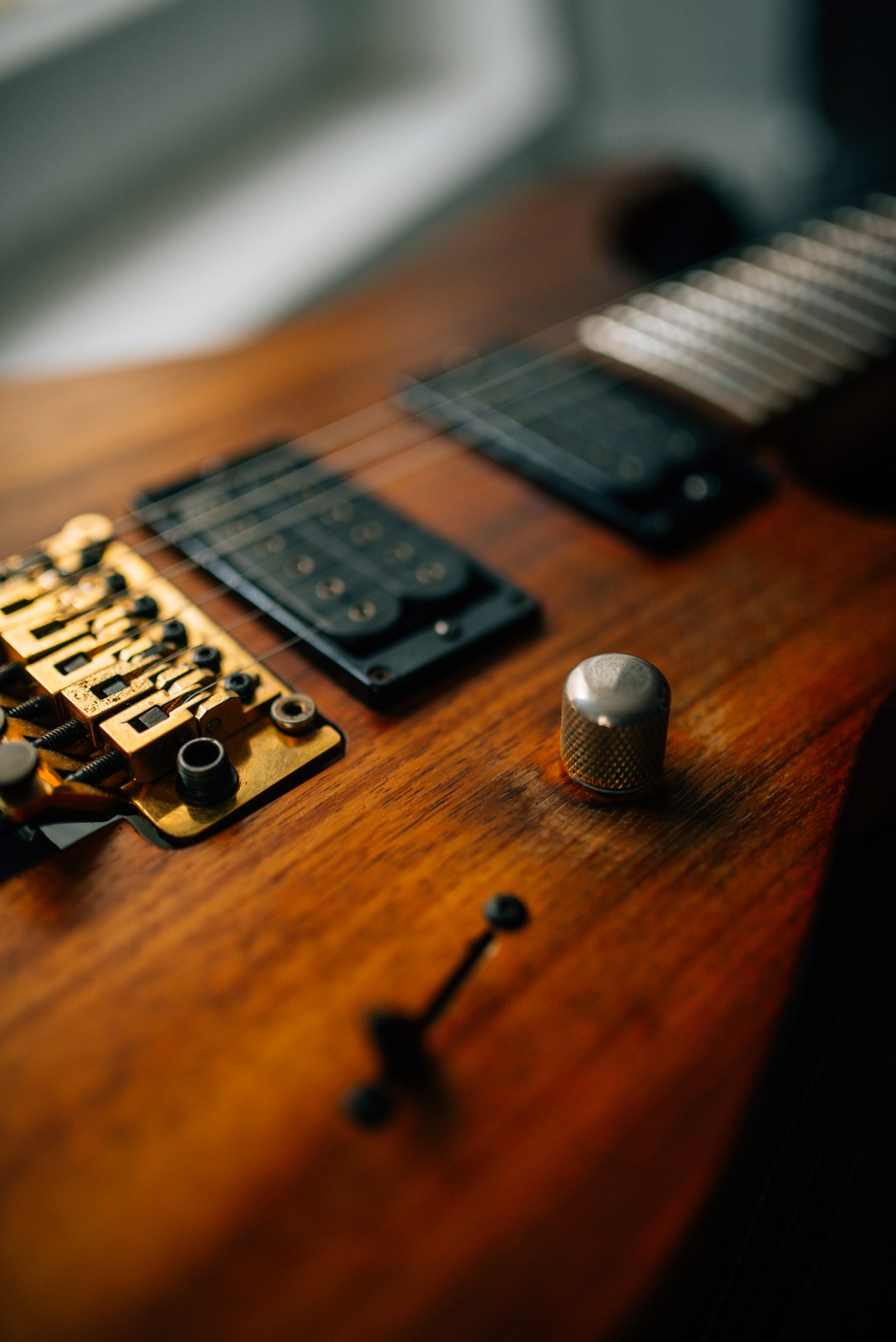 Close-up of a koa Charvel body showing a humbucker, volume knob and pickup selector