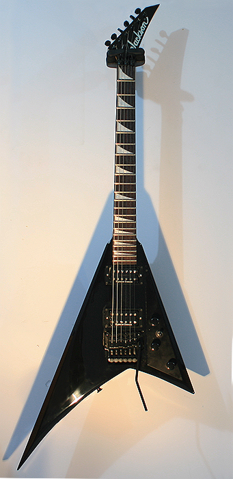Black Jackson Rhoads-shaped guitar hanging on a wall