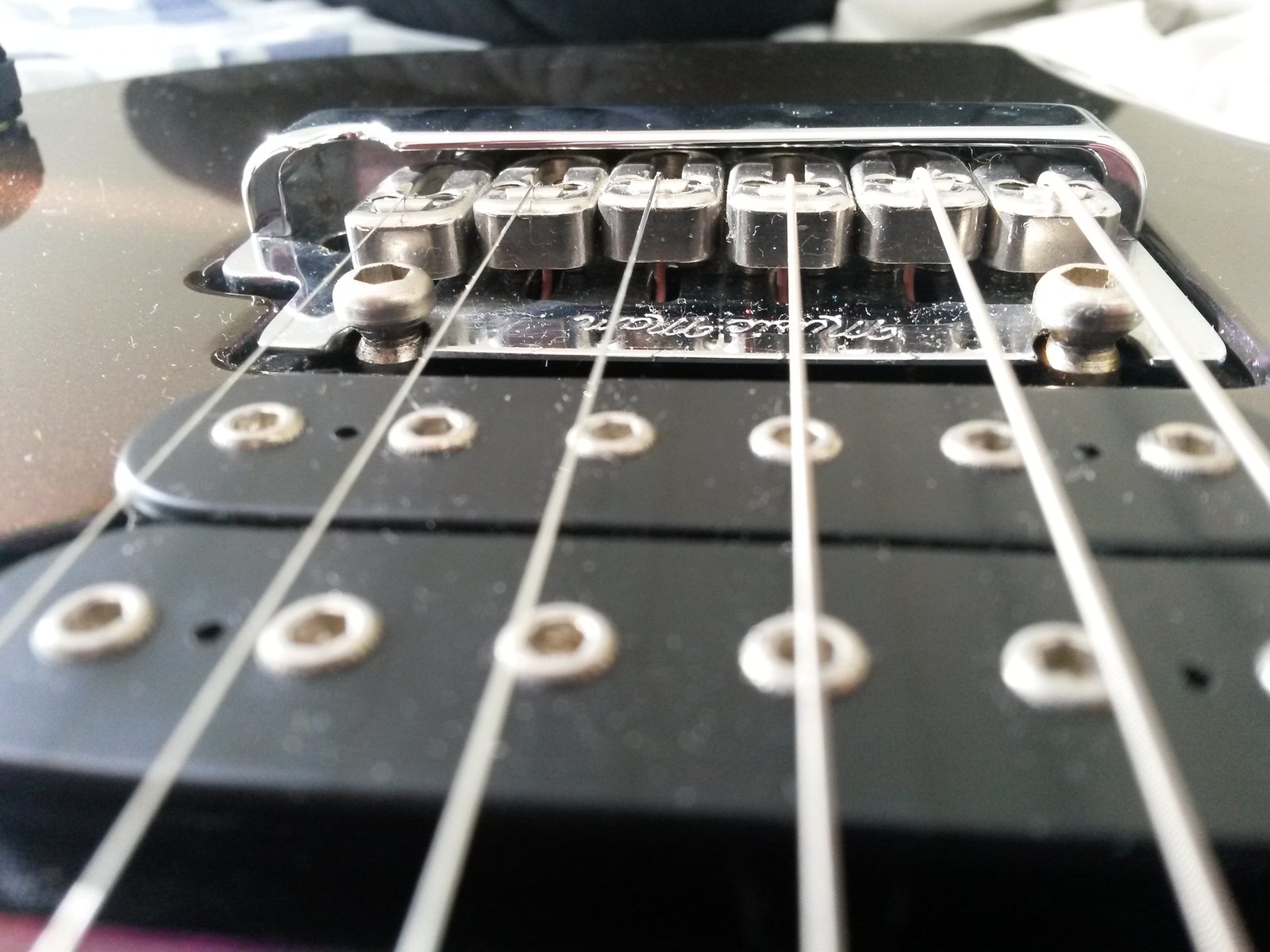 Bridge saddles on a Music Man JP6. A sharp edge or burr where the string crosses the saddle is one of the most common reasons strings keep breaking in the same spot.