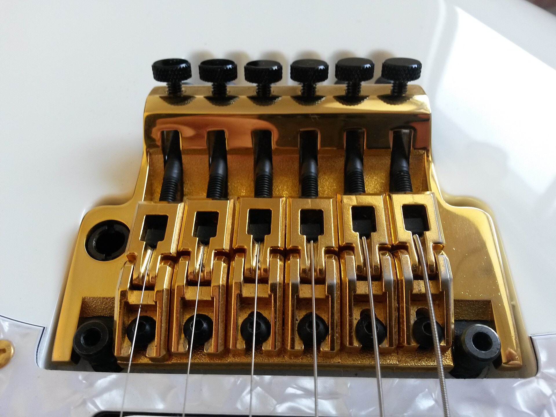 Gold Ibanez Edge tremolo bridge on a white guitar
