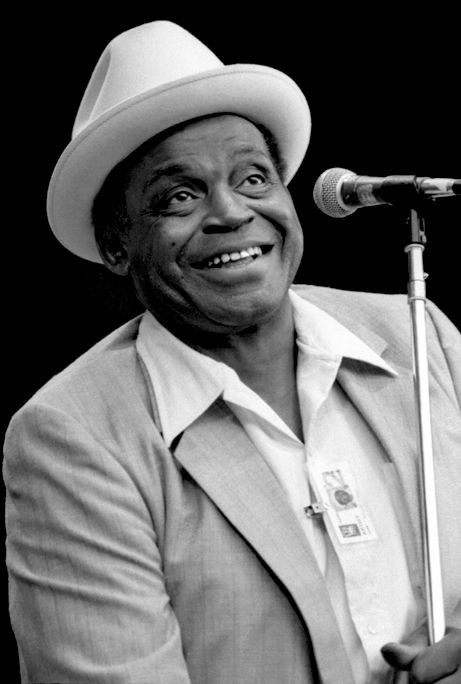 Willie Dixon, wearing a white hat, smiling at a microphone at the Monterey Jazz Festival, 1981