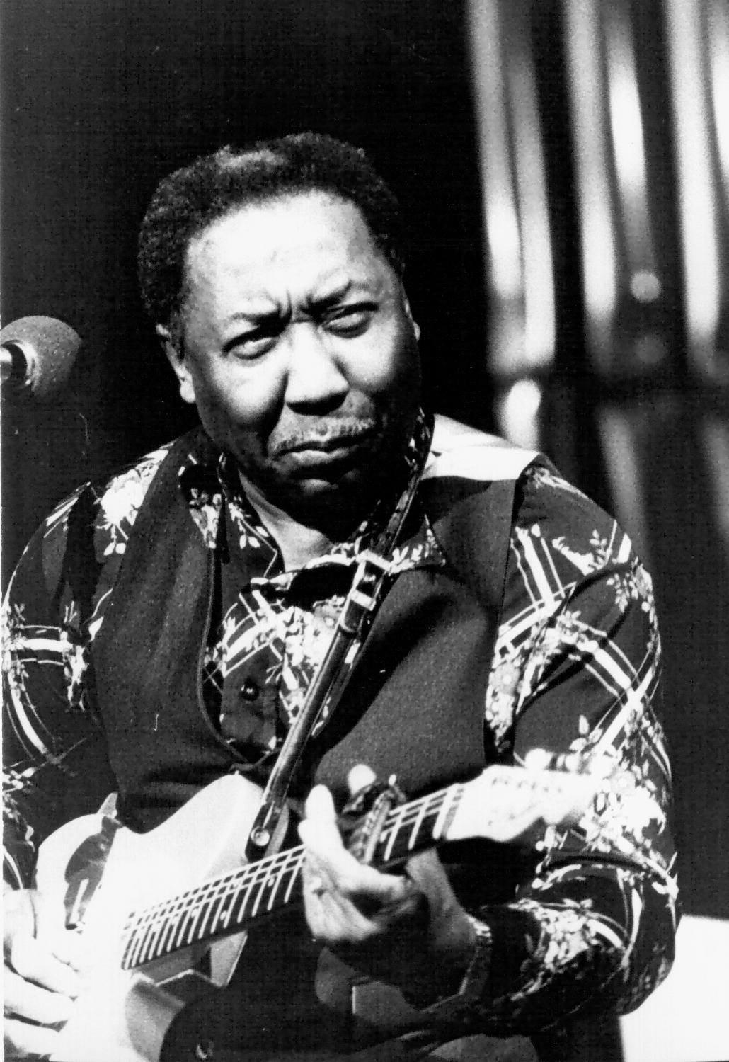 Muddy Waters, seated with an electric guitar, performing in Paris in November 1976