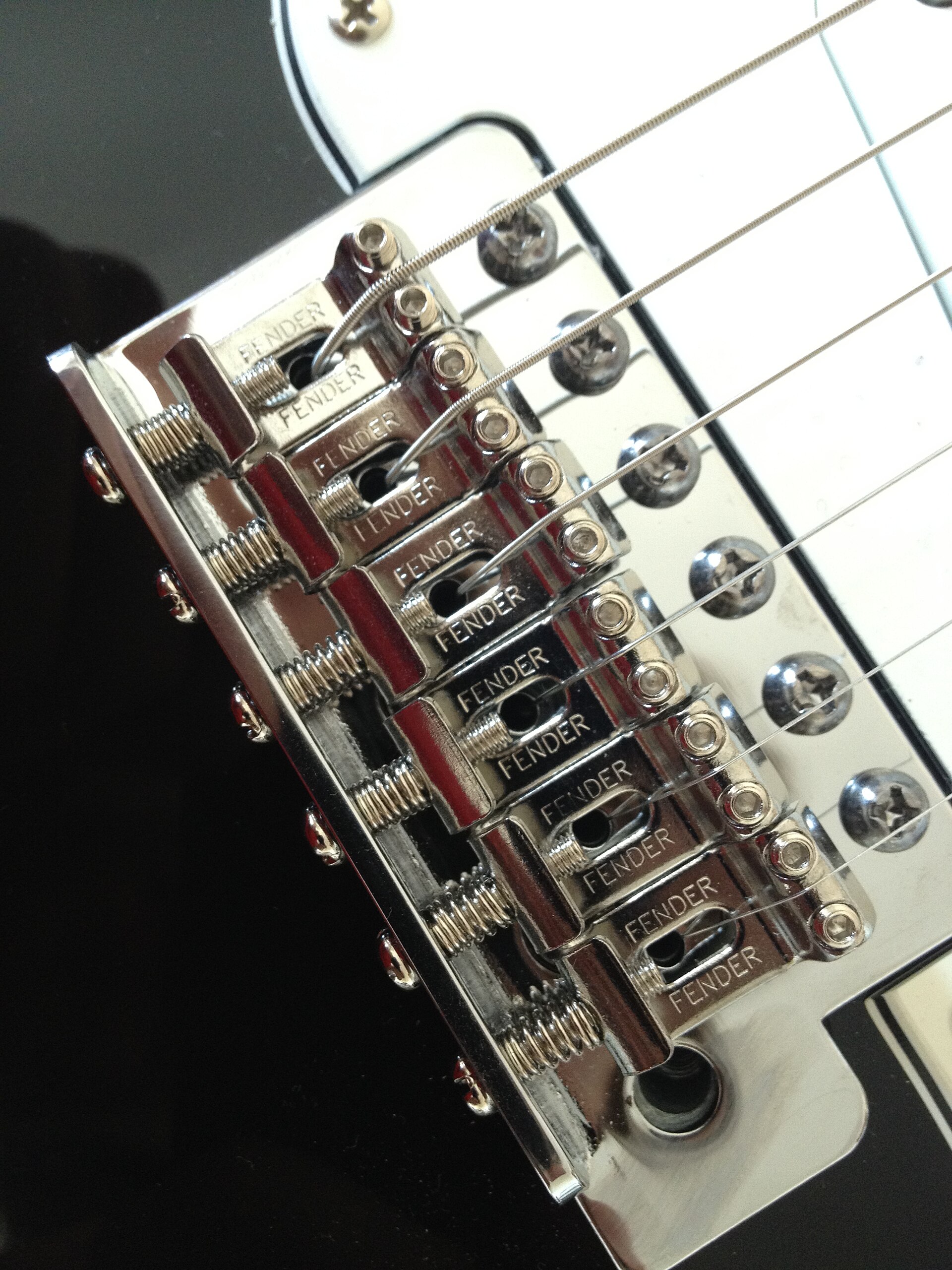 Chrome six-saddle Stratocaster tremolo bridge on a black guitar