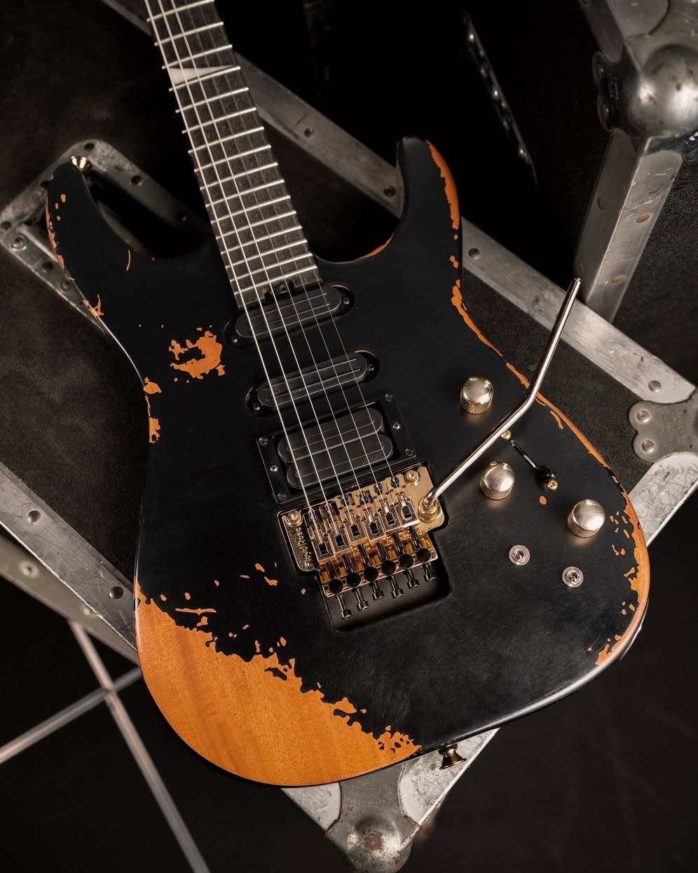 Jackson Pro Series Signature Phil Collen PC1-E in Worn Black with gold hardware, photographed on a flight case