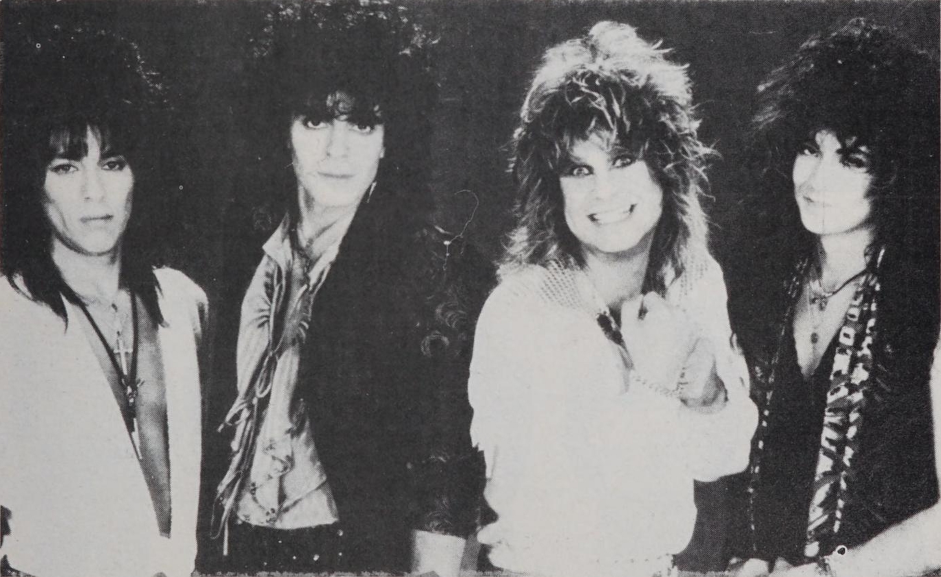 Black-and-white group portrait of four long-haired rock musicians