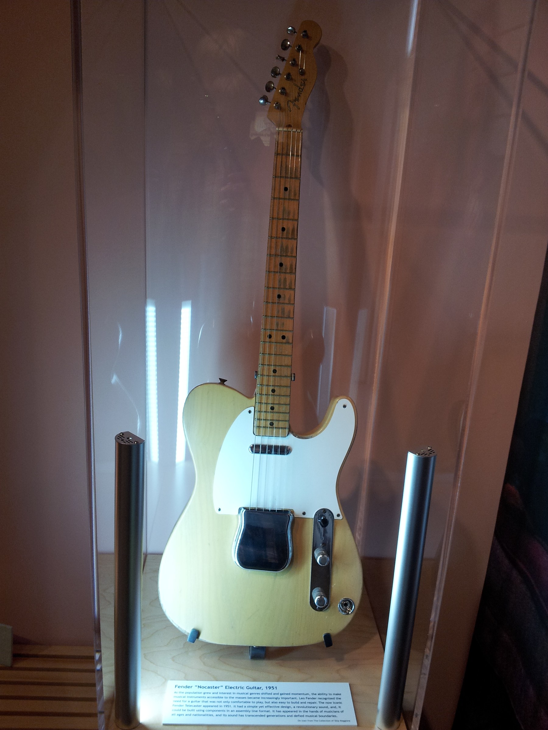 A 1951 Fender Nocaster displayed in a lit museum case