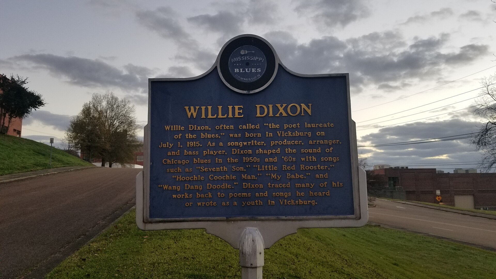 Mississippi Blues Trail historical marker for Willie Dixon in Vicksburg, a blue sign beside a road under a cloudy sky
